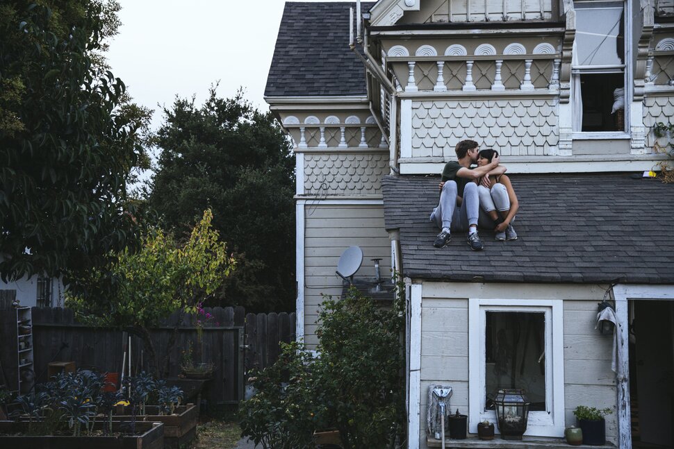 A Graduate couple is enjoying their home while sitting on the roof